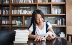 Young woman reading book sitting indoor in urban cafe.